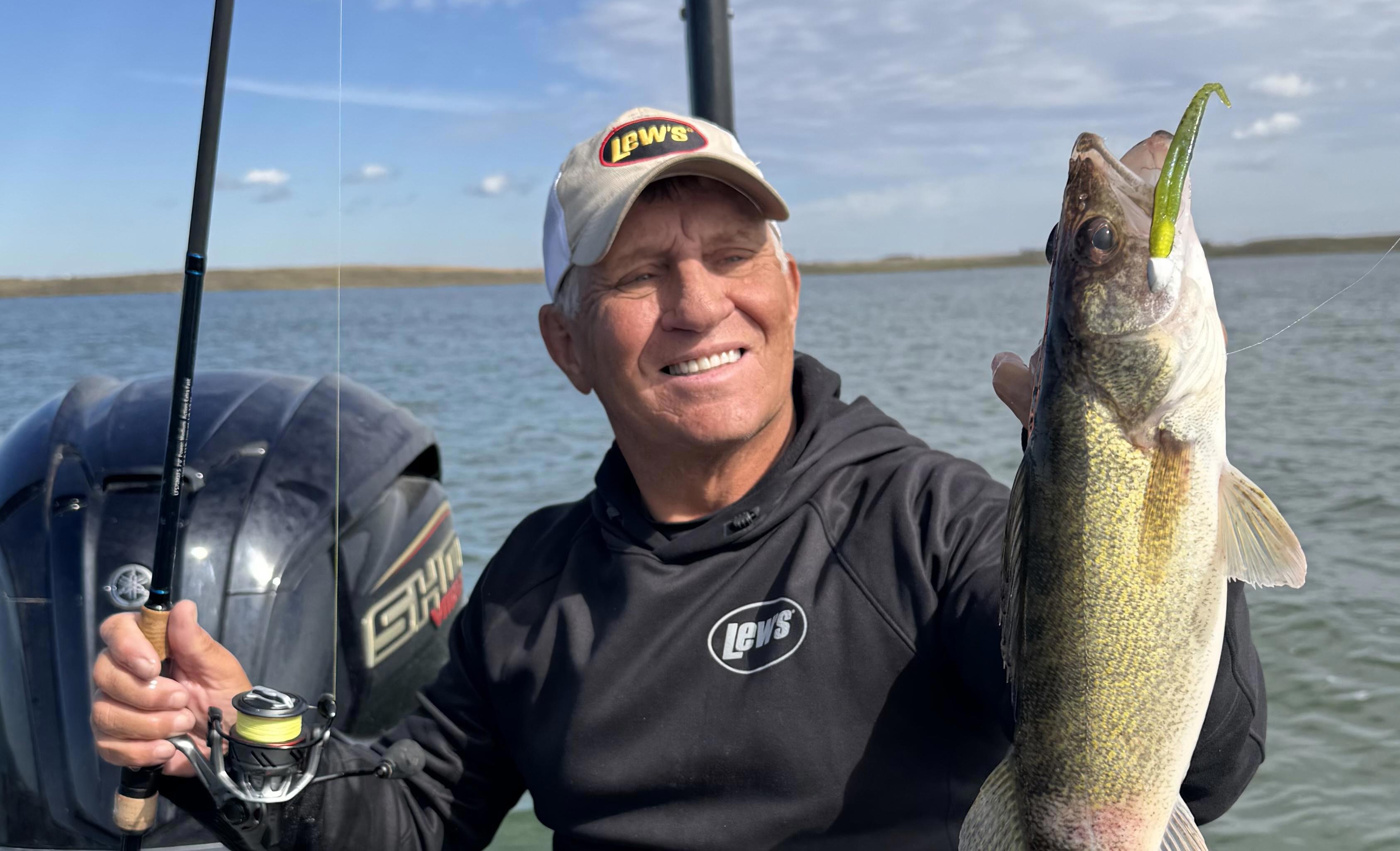 Angler holding a walleye on a boat while fishing