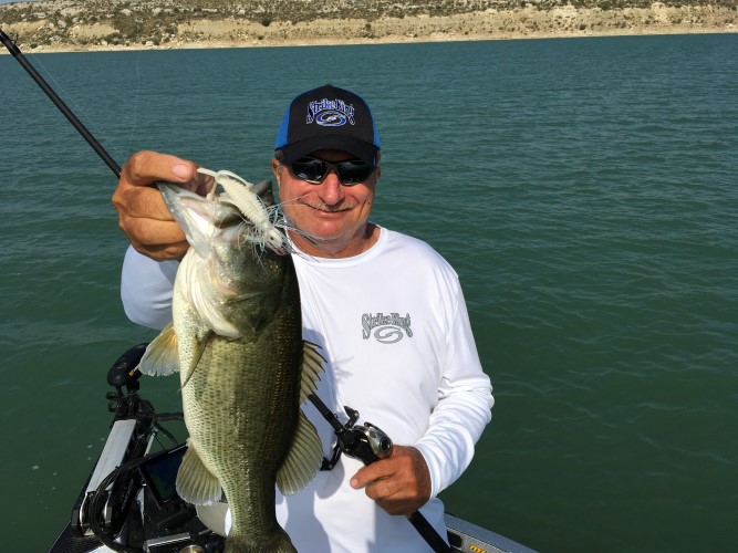 Denny Brauer holding out a bass caught on a Strike King Rage Bug and jig