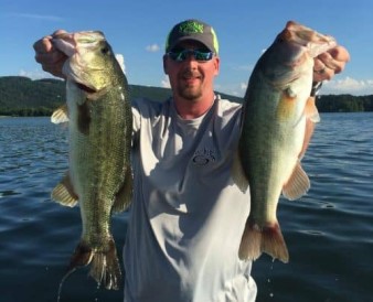 Keith Combs holding out two bass to the camera